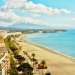 Playa de la Rada beach in Estepona with palm trees and the town backdrop, Costa del Sol