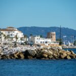 Coastal town on the Costa del Sol with historic tower and marina, illustrating the Estepona vs Marbella property market comparison for British buyers in 2026