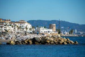 Coastal town on the Costa del Sol with historic tower and marina, illustrating the Estepona vs Marbella property market comparison for British buyers in 2026