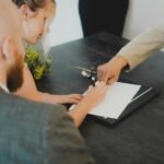 Couple signing property documents at a desk with a Spanish property lawyer