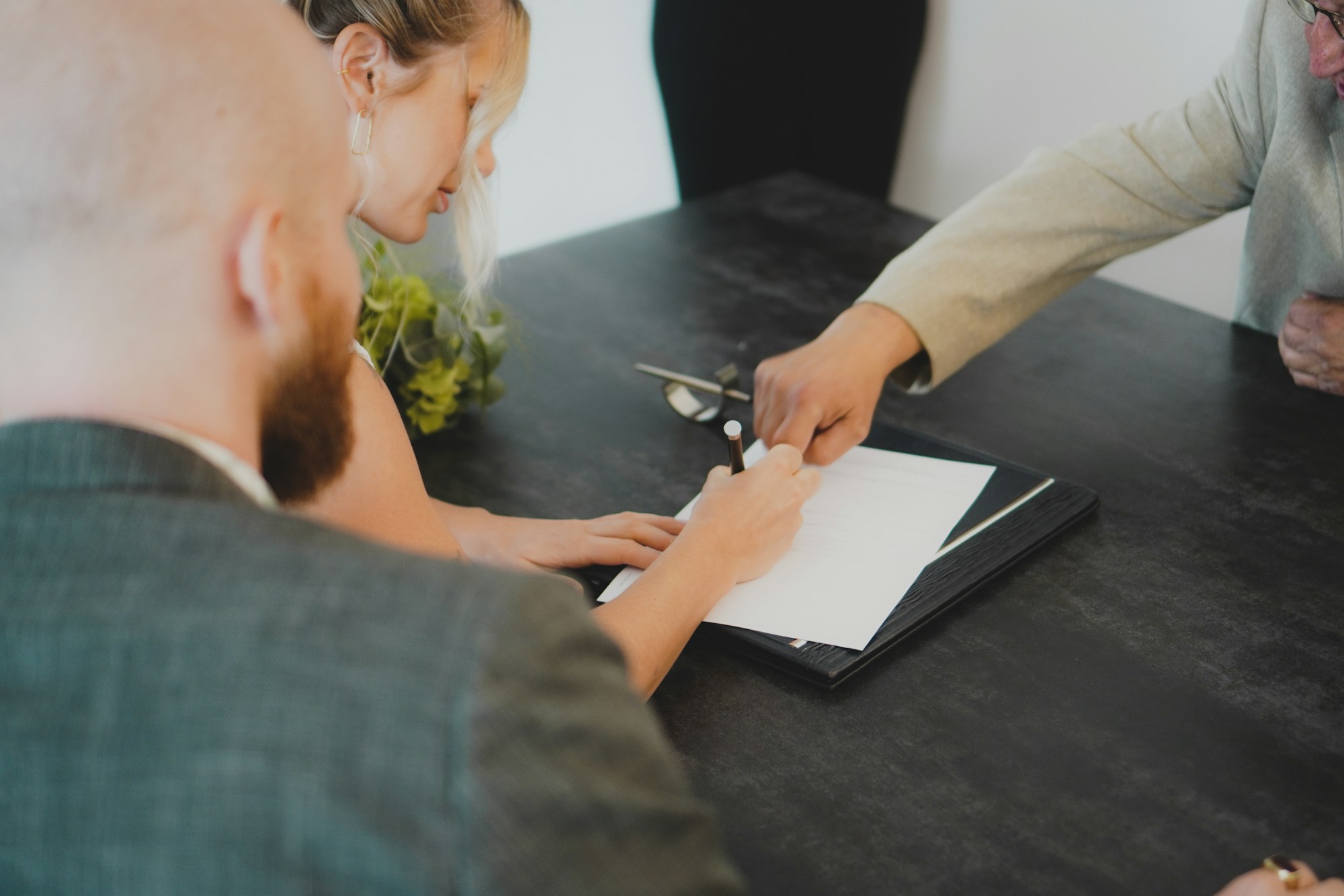 Couple signing property documents at a desk with a Spanish property lawyer