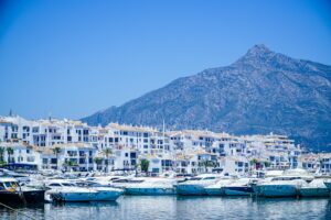 Blue and white boats on the Mediterranean coast of Spain near mountains and a clear blue sky