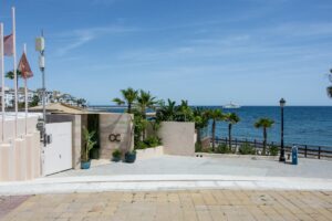 Luxury coastal apartment building with palm trees and blue Mediterranean ocean on the Costa del Sol near San Pedro de Alcantara