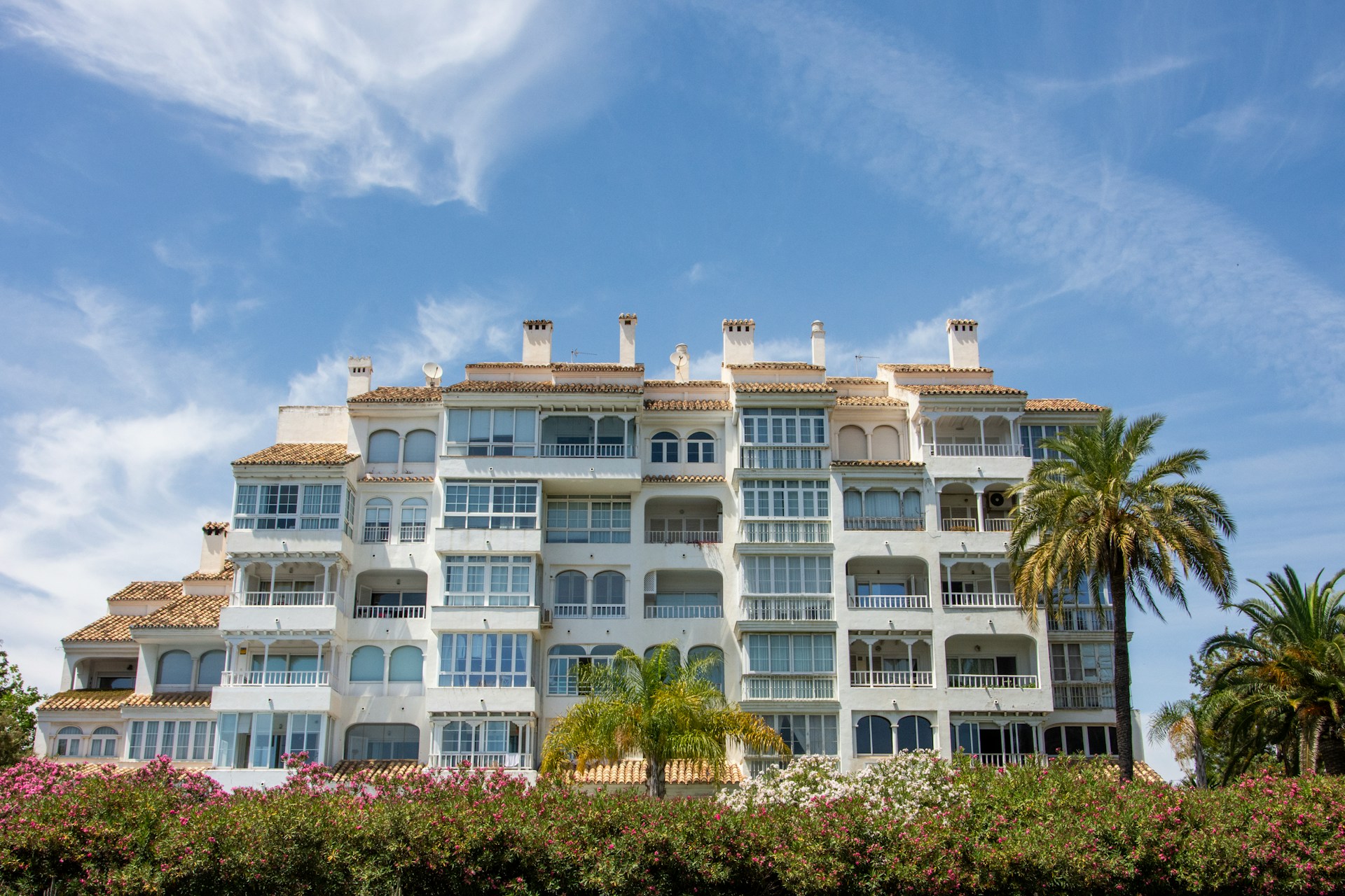 Modern white apartment building with balconies and palm trees on the Costa del Sol, Spain