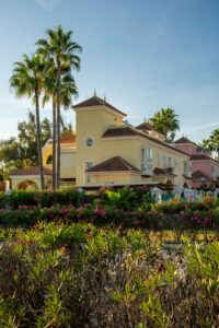 Yellow Mediterranean villa with palm trees and vibrant flowers on the Costa del Sol, Spain